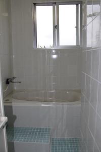 a white bath tub in a bathroom with a window at Guest House Miyakojima in Miyako-jima