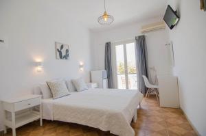 a white bedroom with a bed and a balcony at Avra Pension in Ios Chora