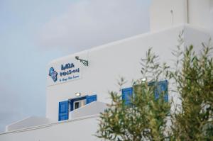 a sign on the side of a building with blue windows at Avra Pension in Ios Chora