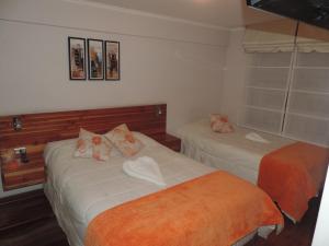 1 dormitorio con 2 camas con sábanas de color naranja en Hotel Paola Antofagasta, en Antofagasta