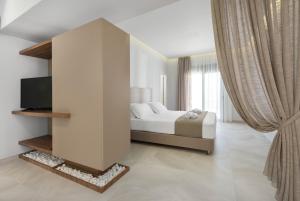 a bedroom with a bed and a tv and curtains at Lardos Luxury Apartments in Lardos