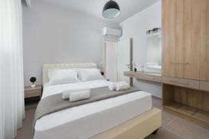 a white bedroom with a large bed and a bathroom at Lardos Luxury Apartments in Lartos