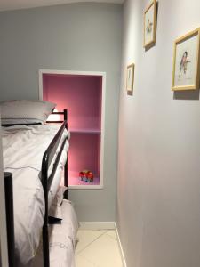 - une chambre avec un lit et un mur rose dans l'établissement Le Cèdre Bleu, à Fouras