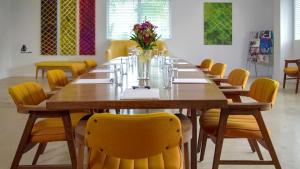 a long wooden table with yellow chairs in a room at The Vagabond Hotel in Miami