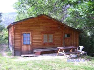 a log cabin with a bench and a picnic table at Ferme La Viste in La Roche-sur-le-Buis