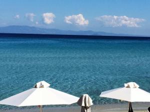 two white umbrellas on a beach with the ocean at Afitos Villa Kristy in Afitos
