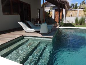 a swimming pool in a backyard with chairs and a house at Villa Saia in Gili Islands