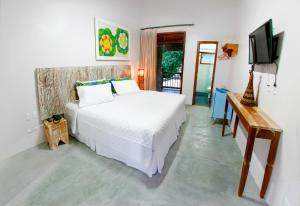 um quarto com uma cama branca e uma televisão em Pousada Villa Maeva Itacare em Itacaré