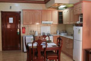 Una cocina con gabinetes de madera y una mesa y sillas. en Apartments Hadaiq AL Khalij For Serviced Apartments شقق حدائق الخليج للشقق المخدومه, en Dammam