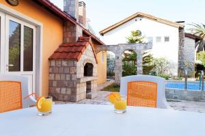 Apart Hotel Apple Cat Montenegro KO Bijela في بييلا: طاولة بيضاء مع كراسي برتقال وعصير برتقال