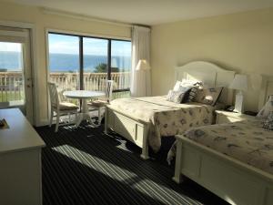 a hotel room with two beds and a balcony at Surf & Sand Beach Motel in South Yarmouth