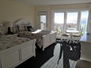 a bedroom with a bed and a table and chairs at Surf & Sand Beach Motel in South Yarmouth