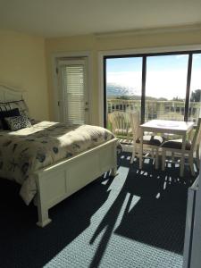 a bedroom with a bed and a table and a balcony at Surf & Sand Beach Motel in South Yarmouth