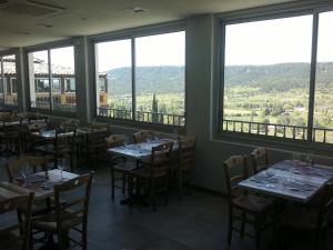 een eetkamer met tafels, stoelen en ramen bij Hotel le Belvédère in Moustiers-Sainte-Marie