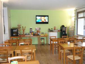 ein Restaurant mit Holztischen und einem TV an der Wand in der Unterkunft Le Faubourg in Figeac