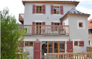 a house with red shutters and a balcony at Le Chalande in Autrans
