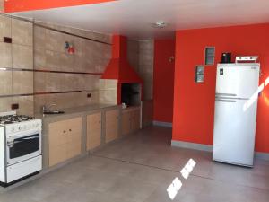 una cucina con frigorifero bianco e pareti rosse di Departamentos a estrenar a Termas de Río Hondo