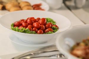 a bowl of tomatoes on a plate on a table at New Space Hotel Airport in Ho Chi Minh City
