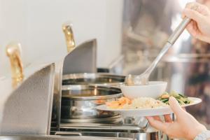a person holding a plate of food in an oven at New Space Hotel Airport in Ho Chi Minh City