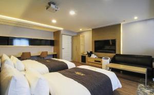 a hotel room with two beds and a flat screen tv at No.1 New Yorker Hotel in Jinju