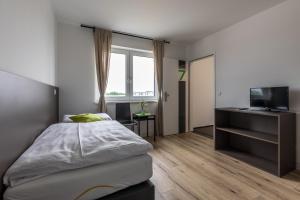 a bedroom with a bed and a tv and a window at Wein4tler-Motel in Gänserndorf