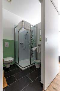 a bathroom with a shower and a toilet at Wein4tler-Motel in Gänserndorf