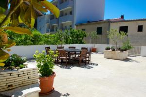 un patio con mesa y sillas frente a un edificio en Apartments Vodanović, en Podgora