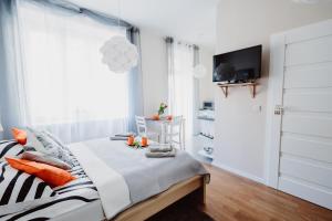 a white bedroom with a bed and a television at Garden Apartment in Krakow