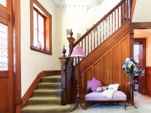 a hallway with a staircase with a pink lamp and a chair at Penghana Bed and Breakfast in Queenstown