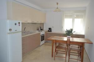 a kitchen with a wooden table and a white refrigerator at Anthi City Center Apartment in Rhodes Town