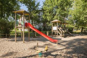 a playground with a red slide and a swing set at Residence Le Domaine de Gascogne - maeva Home in Biscarrosse