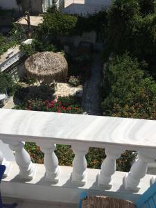 a white bench with a straw umbrella on a garden at Nikoleta Rooms in Tinos