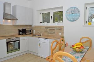 een keuken met witte kasten en een tafel met een fruitschaal bij Braavos in Šibenik