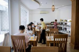 a group of people sitting at tables in a restaurant at New Space Hotel Airport in Ho Chi Minh City