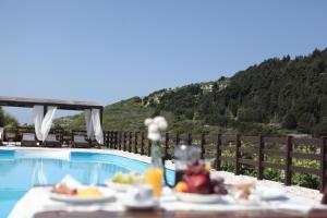 a table with plates of food next to a swimming pool at Paxos Santa Marina Villas in Gaios