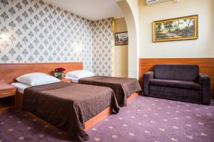 a hotel room with two beds and a chair at Hotel Maksymilian in Krakow