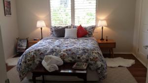 ein Schlafzimmer mit einem Bett, zwei Lampen und einem Fenster in der Unterkunft Winston Cottage at Three Sisters in Katoomba