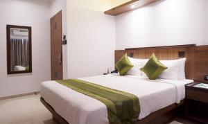 een slaapkamer met een groot wit bed met groene kussens bij Treebo Trend Olive Inn in Mumbai