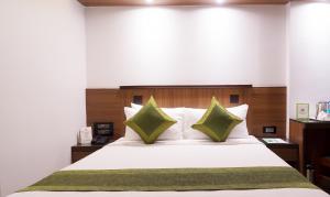 ムンバイにあるツリーボ オリーブ インのベッドルーム(緑の枕が付く大きな白いベッド付)