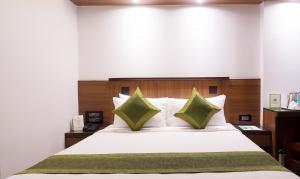 a bedroom with a large white bed with green pillows at Treebo Olive Inn in Mumbai
