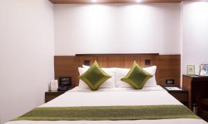 een slaapkamer met een groot wit bed met groene kussens bij Treebo Trend Olive Inn in Mumbai