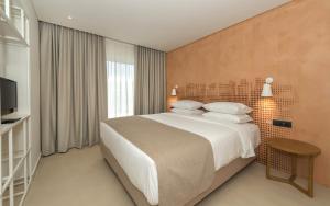 a bedroom with a large bed and a television at Bitzaro Grande Hotel & Suites in Kalamaki