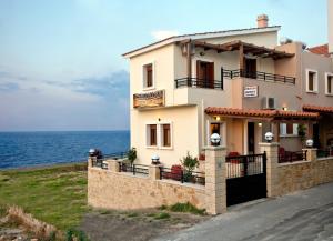 a house on the side of a hill next to the ocean at Apartments Christina in Panormos Rethymno