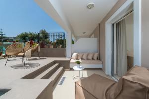 ein Wohnzimmer mit Sofa und Stühlen auf dem Balkon in der Unterkunft Bitzaro Grande Hotel & Suites in Kalamaki