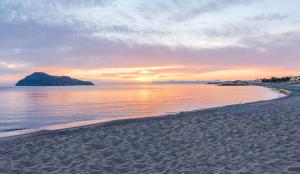 a view of a beach with a sunset in the background at Porto Platanias Beach Resort & Spa in Plataniás