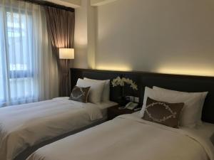 um quarto de hotel com duas camas e um telefone em 晨光飯店 em Chiayi City