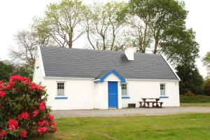 a white cottage with a blue door and a picnic table at Killarney Lakeland Cottages in Killarney