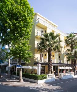 un grand bâtiment jaune avec des palmiers devant lui dans l'établissement Hotel La Nidiola, à Riccione