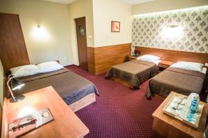 a hotel room with two beds and a table at Hotel Maksymilian in Krakow