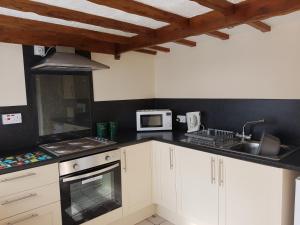 una cocina con armarios blancos y fregadero en Holly Cottage, en Burgh le Marsh